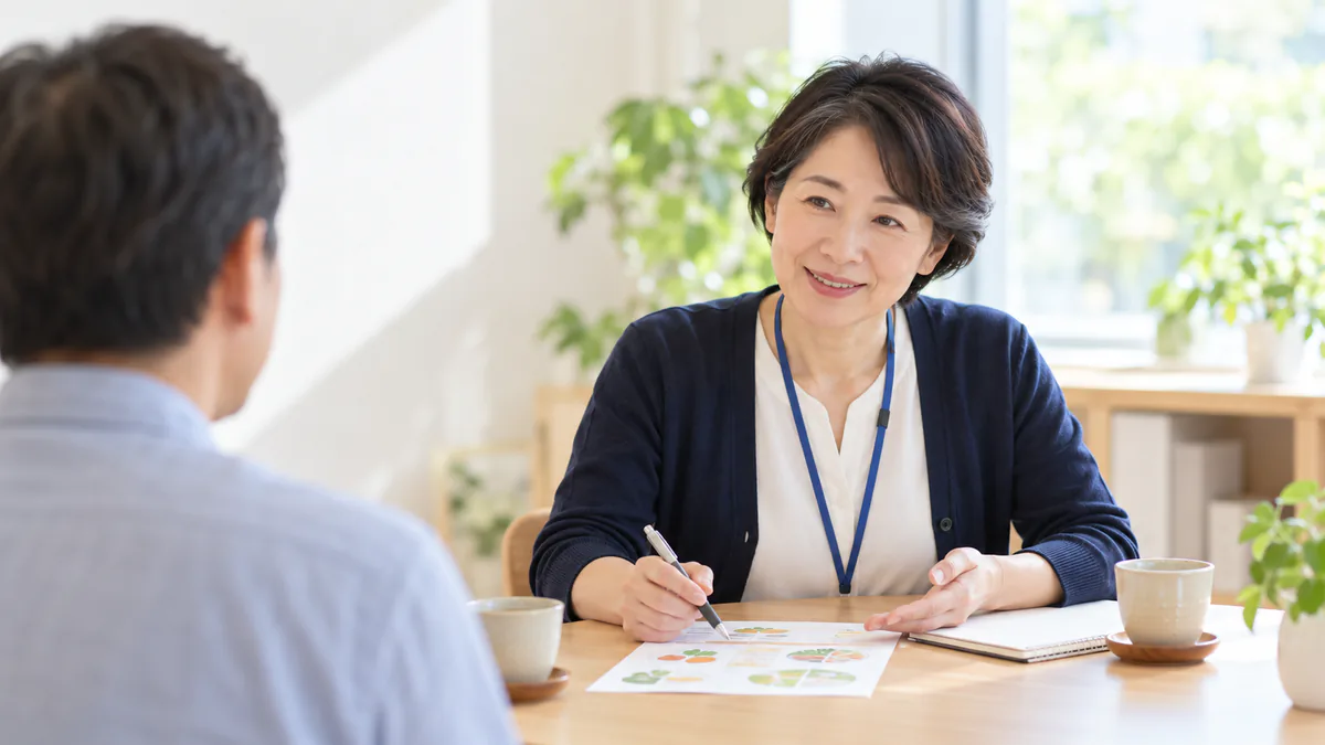 相談に来た方と机をはさんで向かい合い、資料を示しながら話を聞く保健師